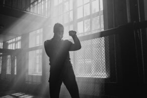 A monochrome image of a boxer training in a sunlit gym, highlighting determination.